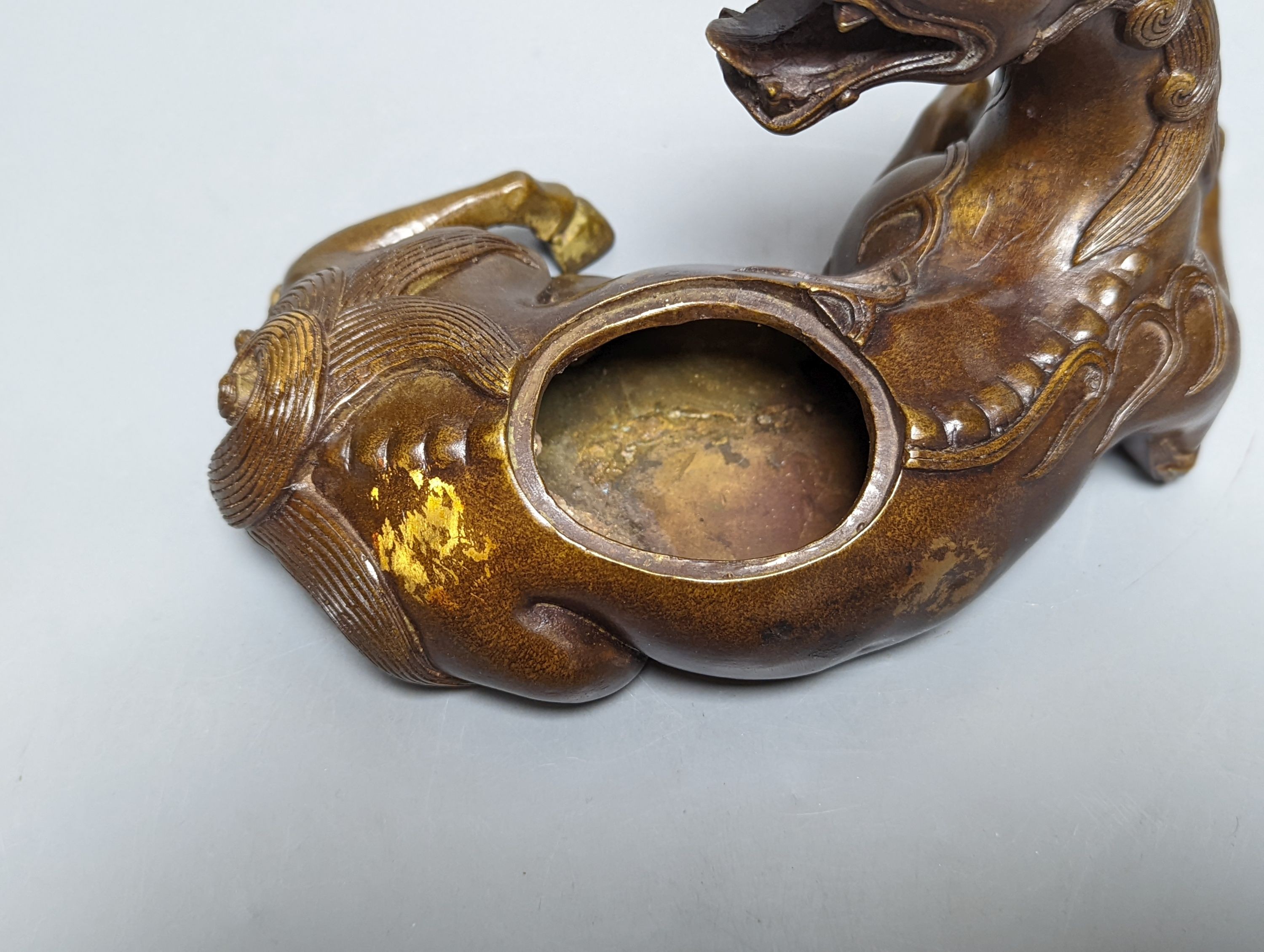 A Chinese parcel-gilt bronze incense burner and cover, modelled as a recumbent qilin, Qing dynasty, 19th century, 25 cms wide.